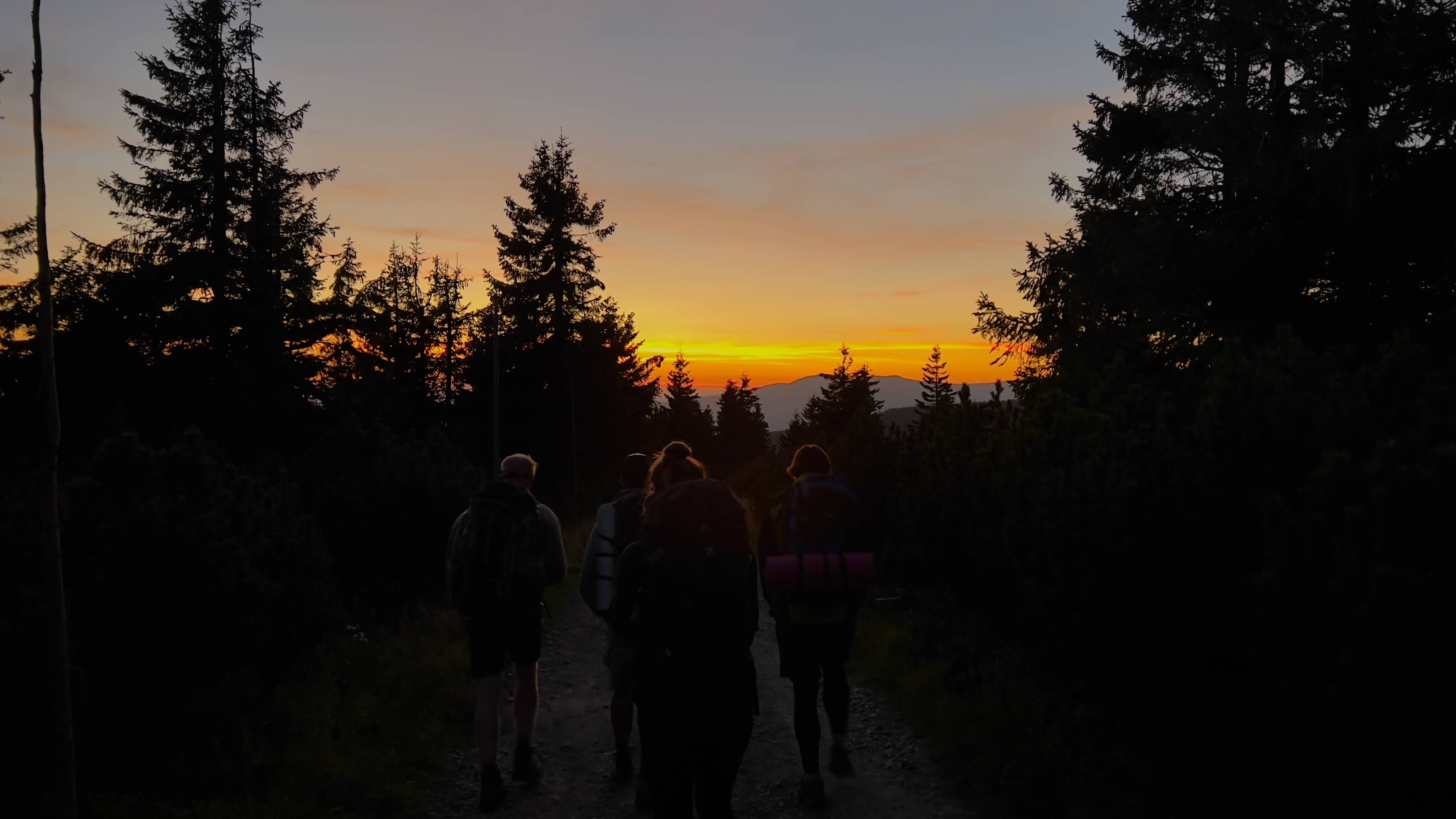 Fotka západu slunce kousek nad Vrchlabím focená zpoza zad čtyř turistů.